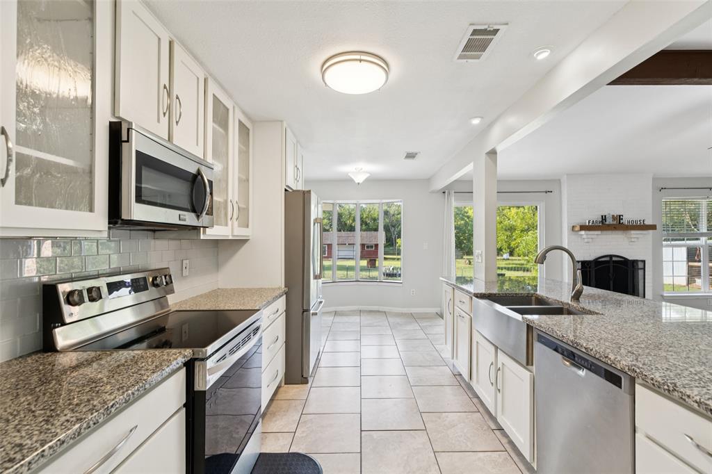 1 Glen Cove Circle Lucas, TX 75002 - Photo 4 of 37 a kitchen with stainless steel appliances granite countertop a sink a stove top oven a chimney cabinets and a counter top space