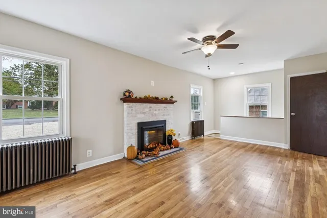 a view of a livingroom with a fireplace a ceiling fan and windows
