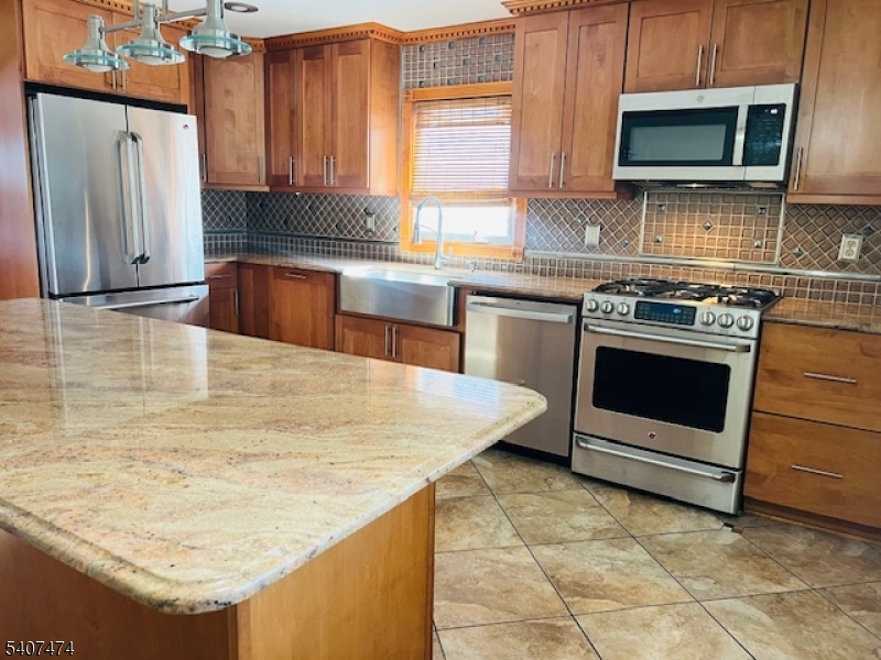 a kitchen with stainless steel appliances granite countertop a stove a sink and a microwave