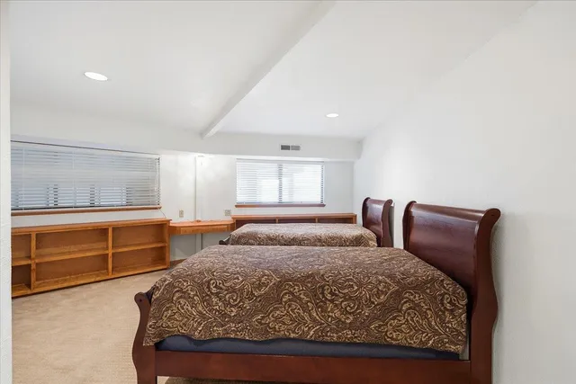 a view of a white house with a large tree and wooden fence