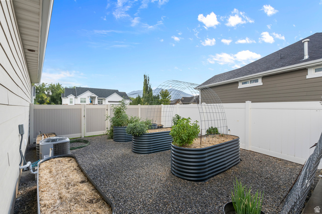 886 River Ridge Lane Spanish Fork, UT 84660 - Photo 25 of 31 Landscaped backyard featuring multiple raised garden beds, gravel ground cover, and full perimeter fencing