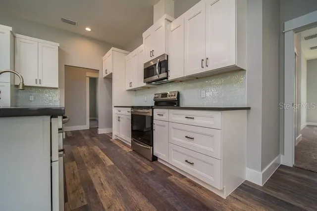 a kitchen with stainless steel appliances white cabinets and a refrigerator