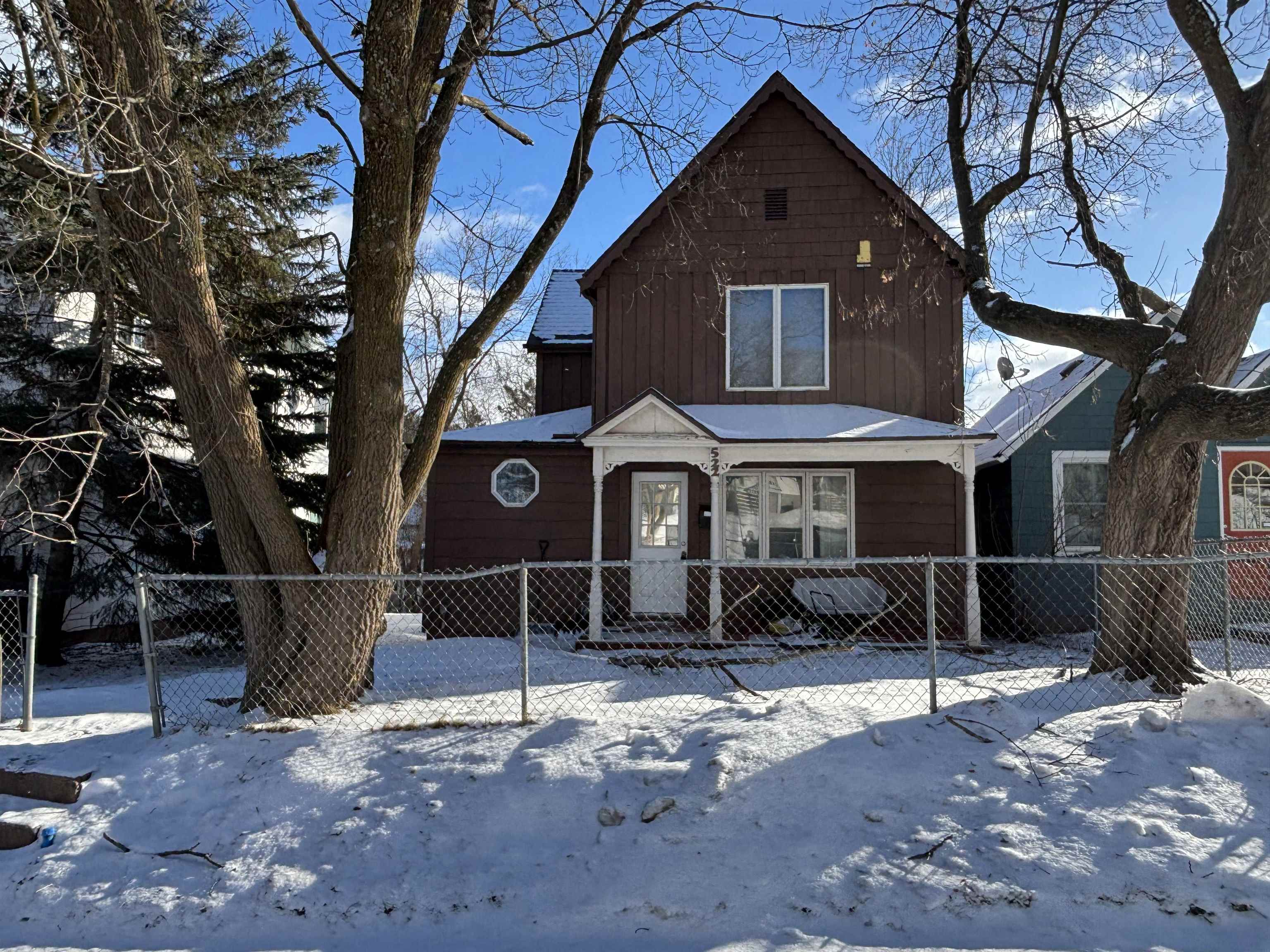 Rustic home with a fenced front yard, covered porch, and a gate