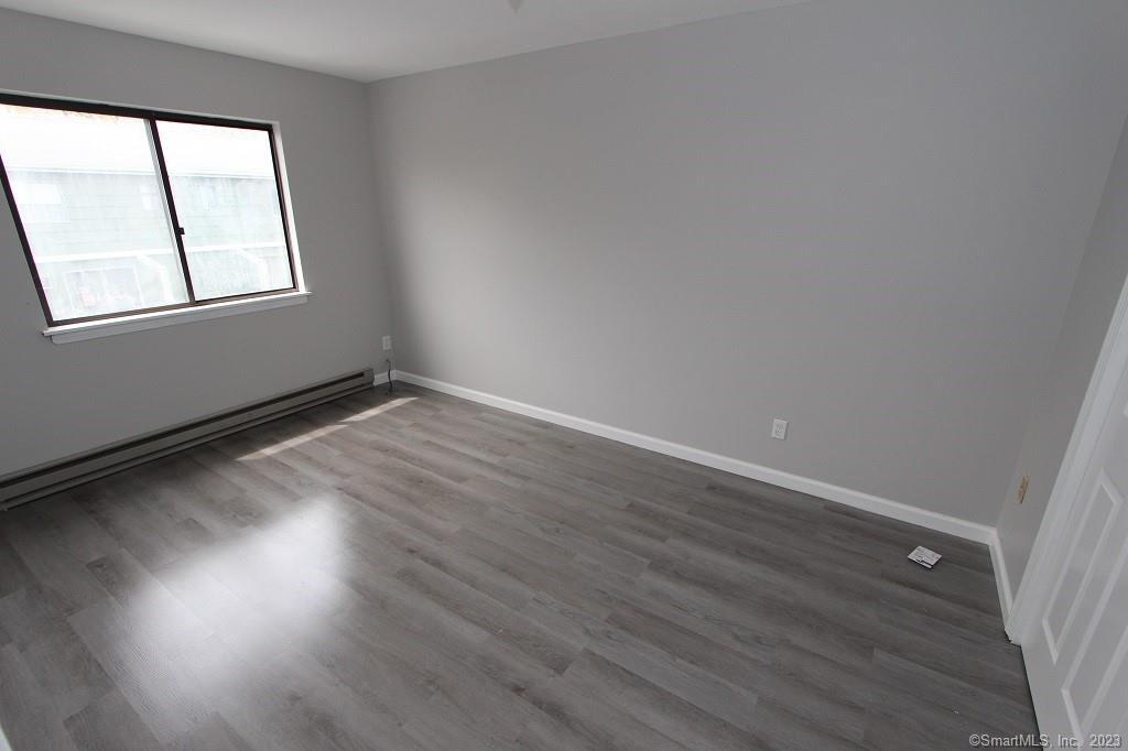 1400 Meriden Road, Unit 52 Waterbury, CT 06705 - Photo 17 of 21 an empty room with wooden floor and windows