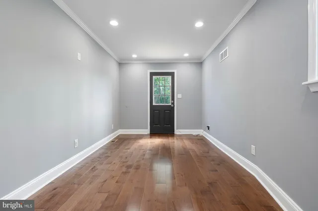 a view of an empty room with wooden floor and windows