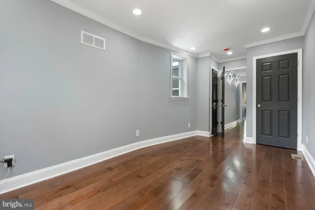 a view of an empty room with wooden floor and closet