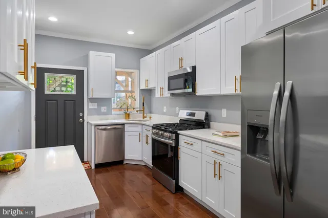 a kitchen with stainless steel appliances a sink a stove a refrigerator cabinets and a window