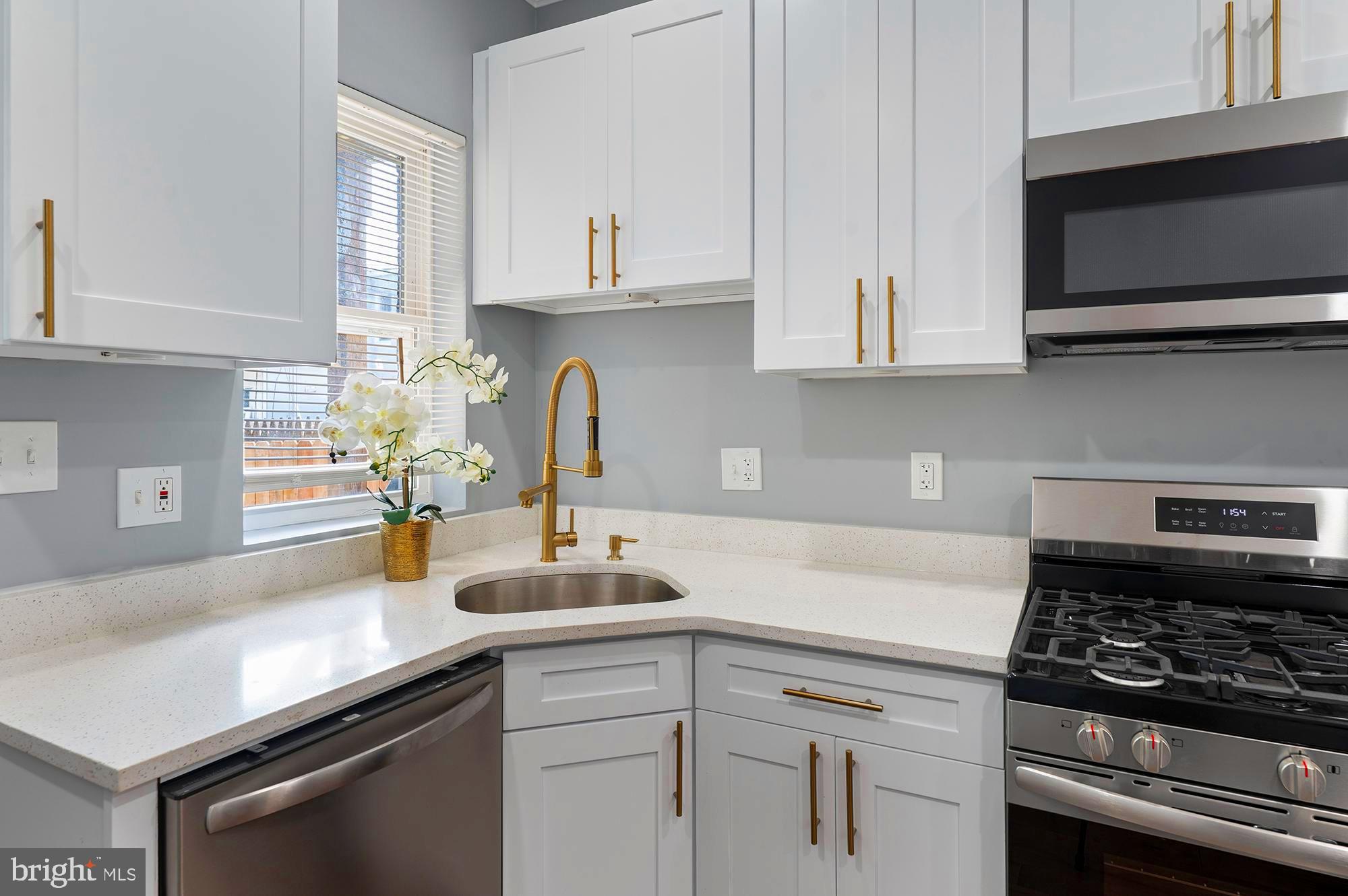 1513 North Wolfe Street Baltimore, MD 21213 - Photo 10 of 33 a kitchen with stainless steel appliances a sink dishwasher stove and white cabinets with wooden floor