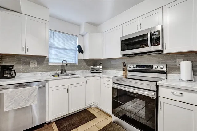 a kitchen with stainless steel appliances granite countertop a sink dishwasher a stove microwave and oven with white cabinets