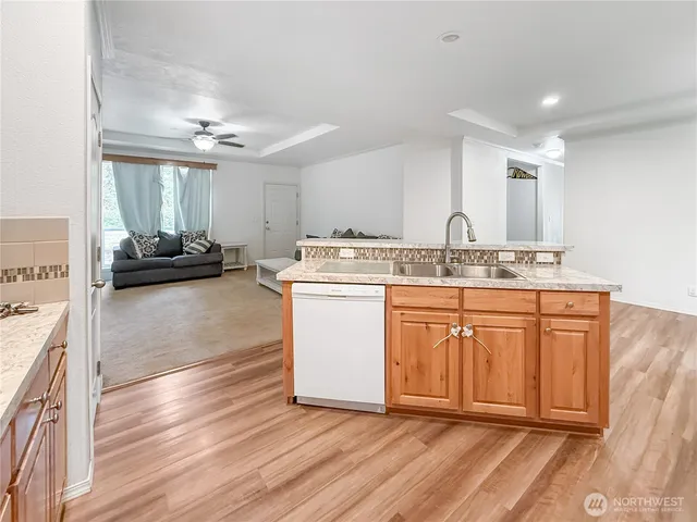 a kitchen with stainless steel appliances granite countertop a sink dishwasher and a stove with wooden floor