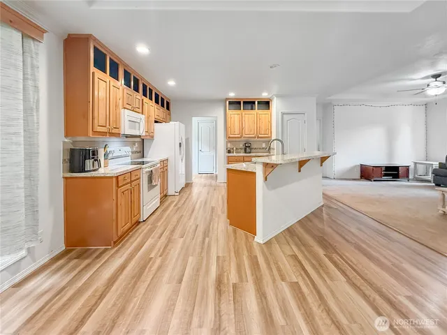 a large white kitchen with wooden floors and stainless steel appliances