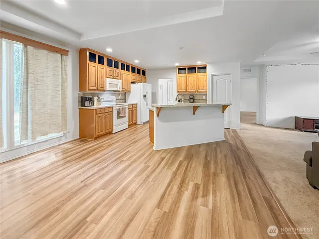 a living room with stainless steel appliances furniture a large window and a wooden floor