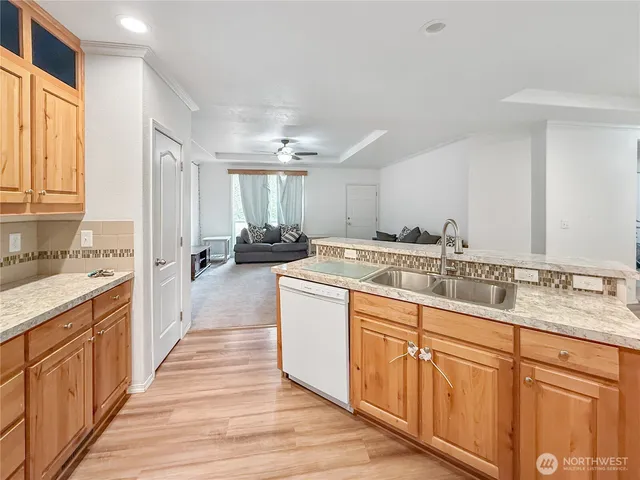 a large kitchen with a large counter top space a sink a window and stainless steel appliances