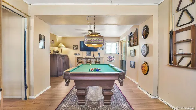 a room with wooden floor pool table and windows