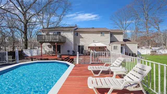 a view of a patio with table and chairs under an umbrella with a barbeque
