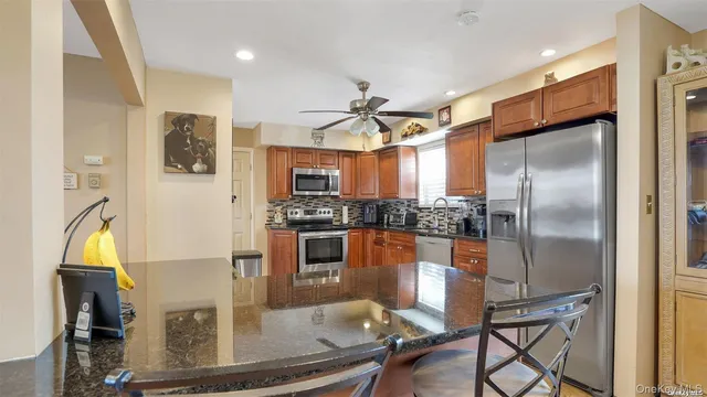 a kitchen with stainless steel appliances granite countertop a refrigerator a stove and a sink with wooden floor