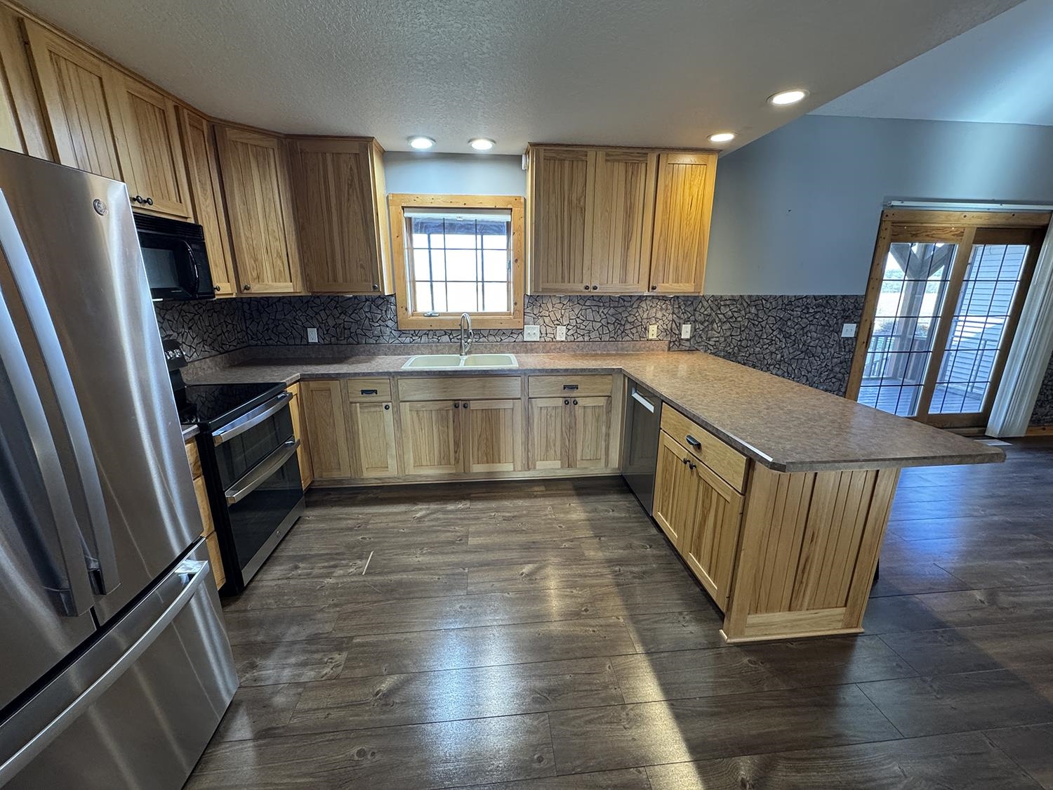 7876 Hickory Grove Road Savanna, IL 61074 - Photo 17 of 67 a kitchen with stainless steel appliances granite countertop a stove a sink dishwasher a refrigerator and wooden floor