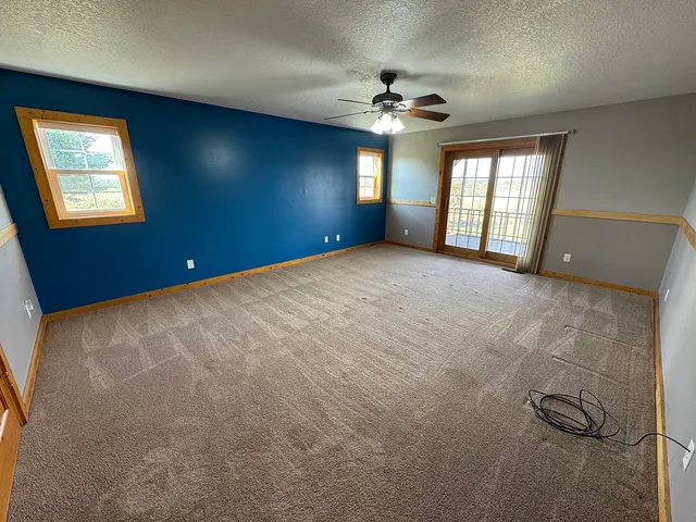 an empty room with windows and fan