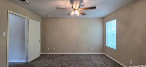 an empty room with windows and fan