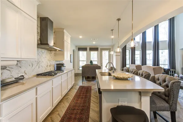 a large kitchen with kitchen island a stove a sink a dining table and chairs