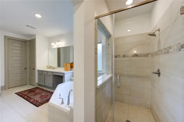 a bathroom with a tub shower sink and mirror
