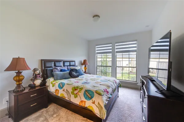 a bedroom with a bed and a flat tv screen on a dresser