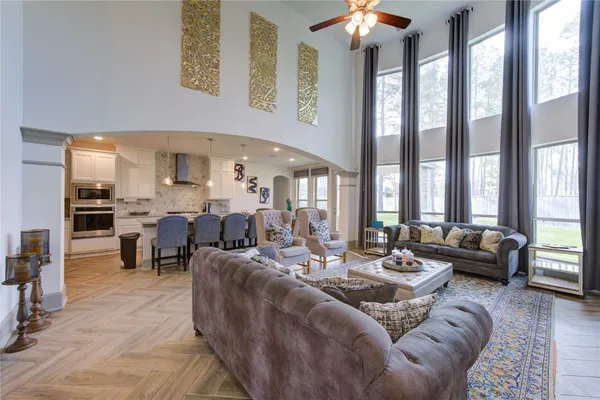 a living room with furniture kitchen area and large windows