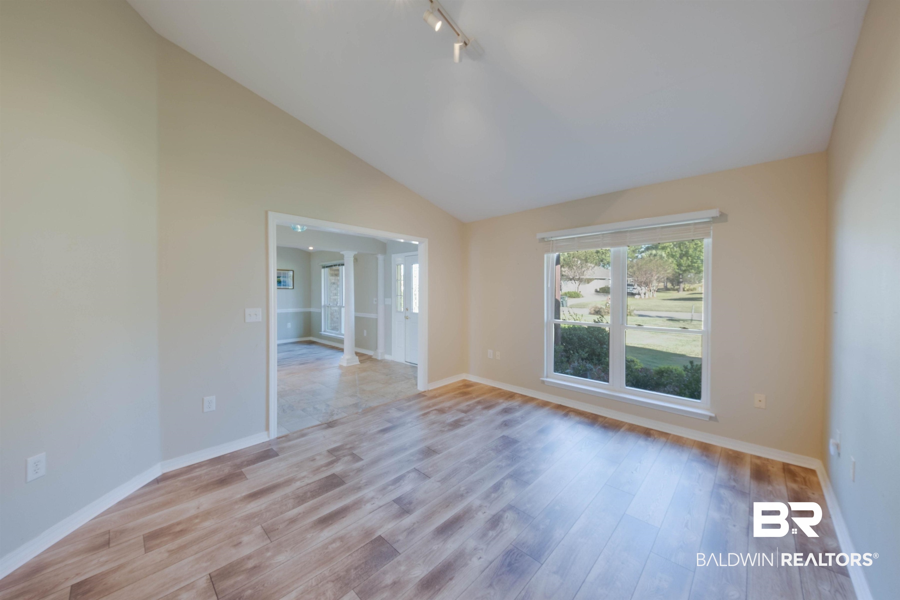 9462 Lakeview Drive Foley, AL 36535 - Photo 4 of 50 Empty room with lofted ceiling, decorative columns, rail lighting, and light wood-type flooring