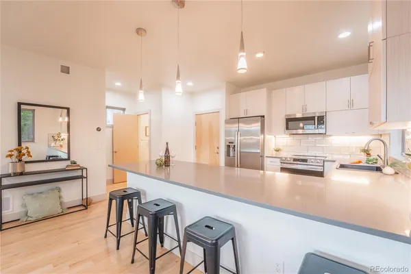 a kitchen with stainless steel appliances a sink a stove a refrigerator cabinets and chairs