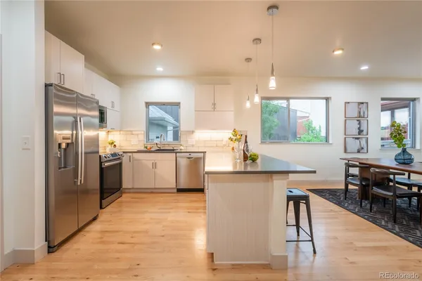 a kitchen with stainless steel appliances kitchen island a refrigerator a stove a sink a dining table and chairs