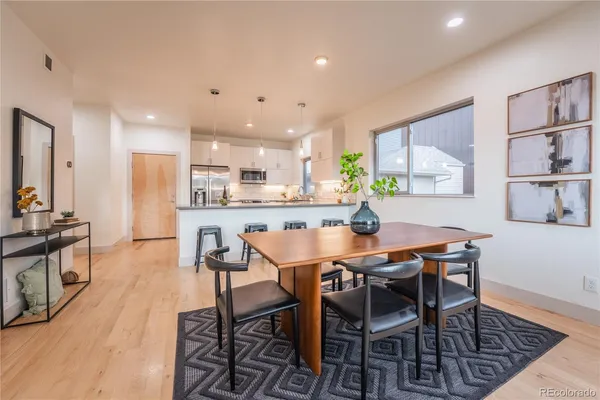 a dining room with stainless steel appliances kitchen island granite countertop a table chairs and a refrigerator