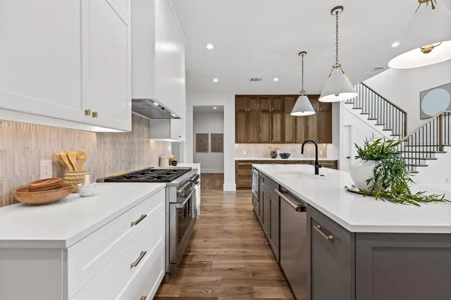 a kitchen with stainless steel appliances granite countertop a lot of counter space and wooden floors