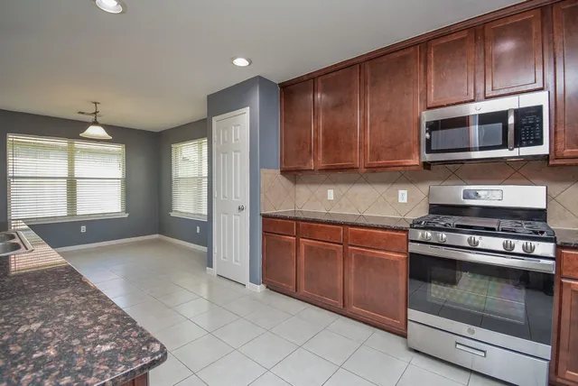 a kitchen with stainless steel appliances granite countertop a stove a microwave and a sink