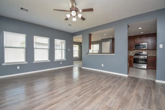 a view of an empty room with window and wooden floor
