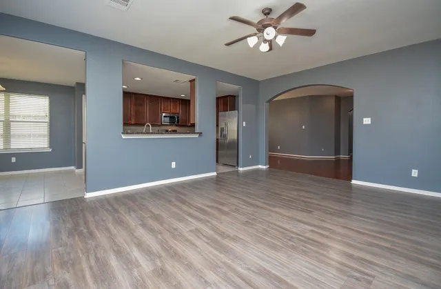 a view of an empty room with window and wooden floor