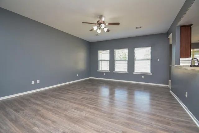 a view of an empty room with a window and wooden floor