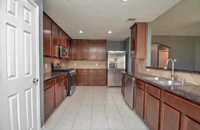 a large kitchen with stainless steel appliances lots of counter space cabinets a sink and a large window