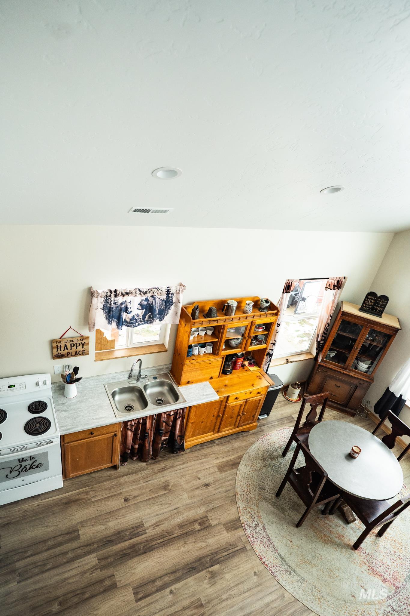 22 West Prospectors Drive Cascade, ID 83611 - Photo 10 of 29 Bar area with light wood-type flooring, light countertops, brown cabinetry, and white electric stove