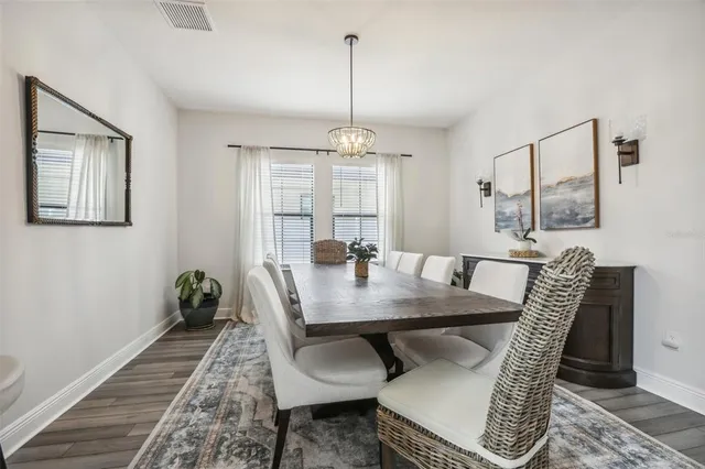 a kitchen with stainless steel appliances kitchen island granite countertop a dining table chairs and white cabinets