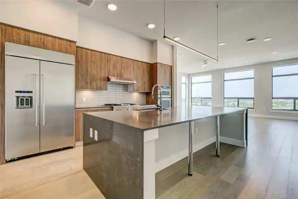 a kitchen with kitchen island a counter top space a sink a refrigerator and a window