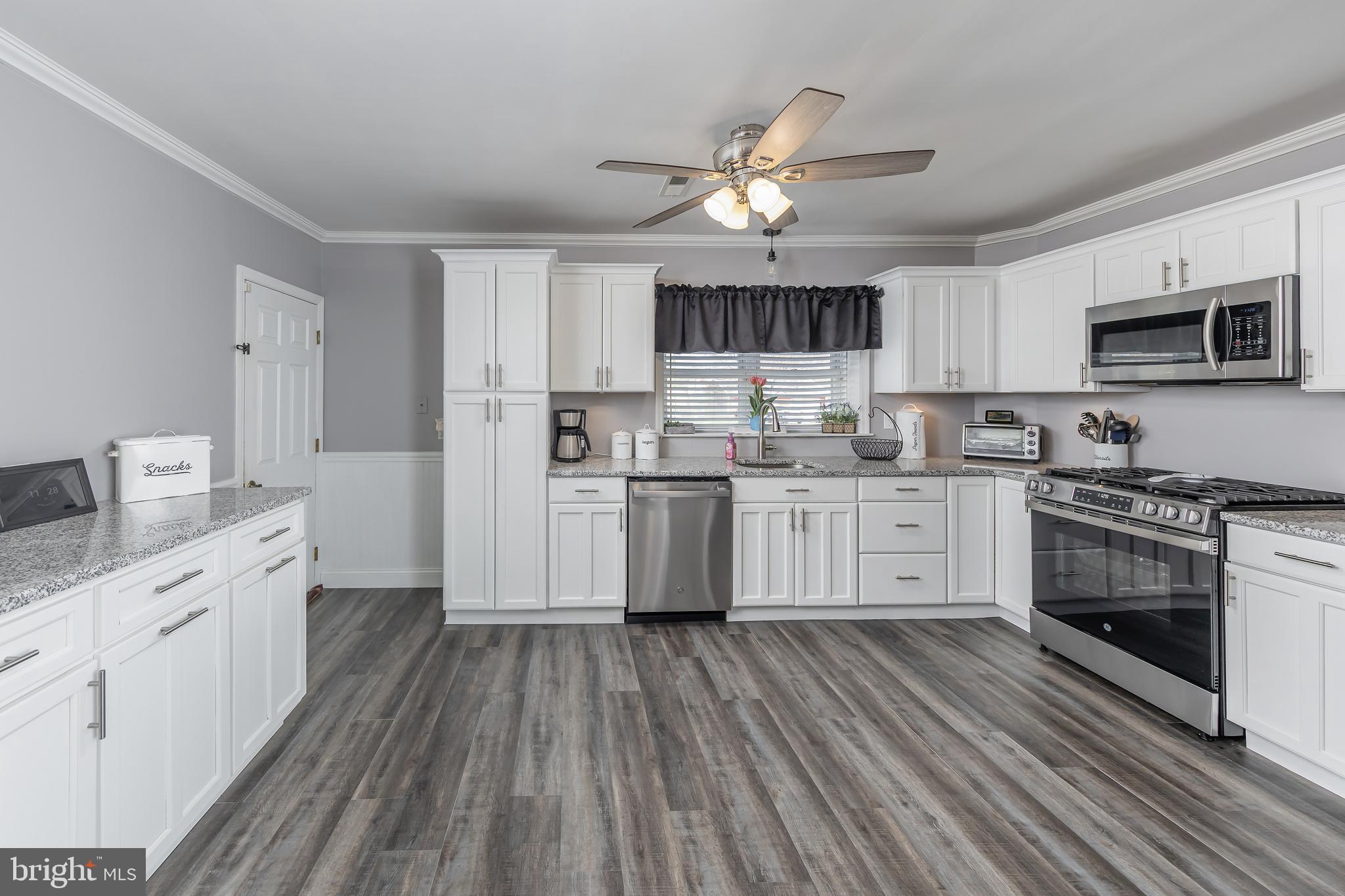 303 Main Street Mantua, NJ 08051 - Photo 6 of 50 a kitchen with stainless steel appliances a white stove top oven a sink dishwasher and a refrigerator with wooden floor