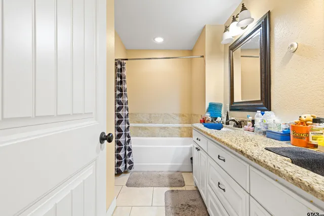a bathroom with a granite countertop sink and a bathtub