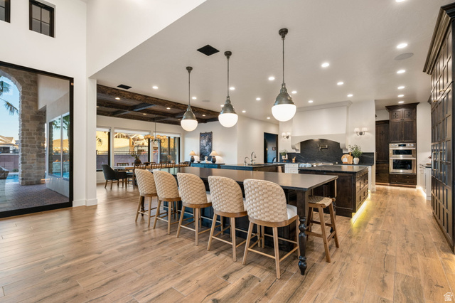 4871 South Homestead Way Washington, UT 84780 - Photo 20 of 151 Kitchen with dark wood finish cabinetry, hanging light fixtures, a breakfast bar area, light wood-style flooring, and decorative backsplash