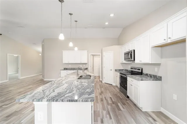 a large kitchen with kitchen island a stove a sink a refrigerator and a granite counter tops