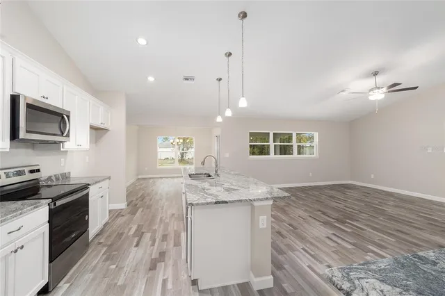 a kitchen with granite countertop cabinets stainless steel appliances a sink and a wooden floor
