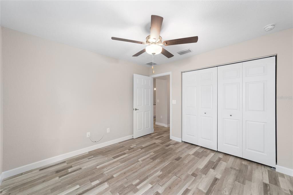 11339 Southwest 65th Ave Road Ocala, FL 34476 - Photo 35 of 42 an empty room with wooden floor ceiling fan and windows