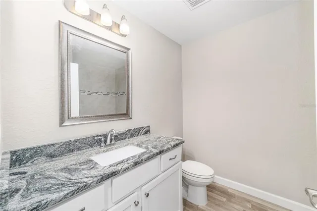 a bathroom with a granite countertop sink a toilet and mirror
