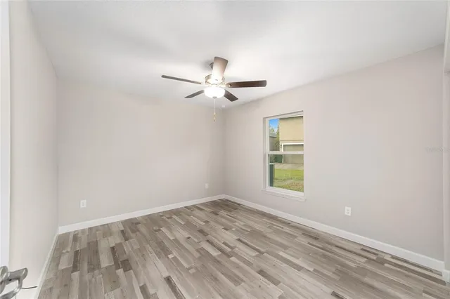 an empty room with a window and a fan
