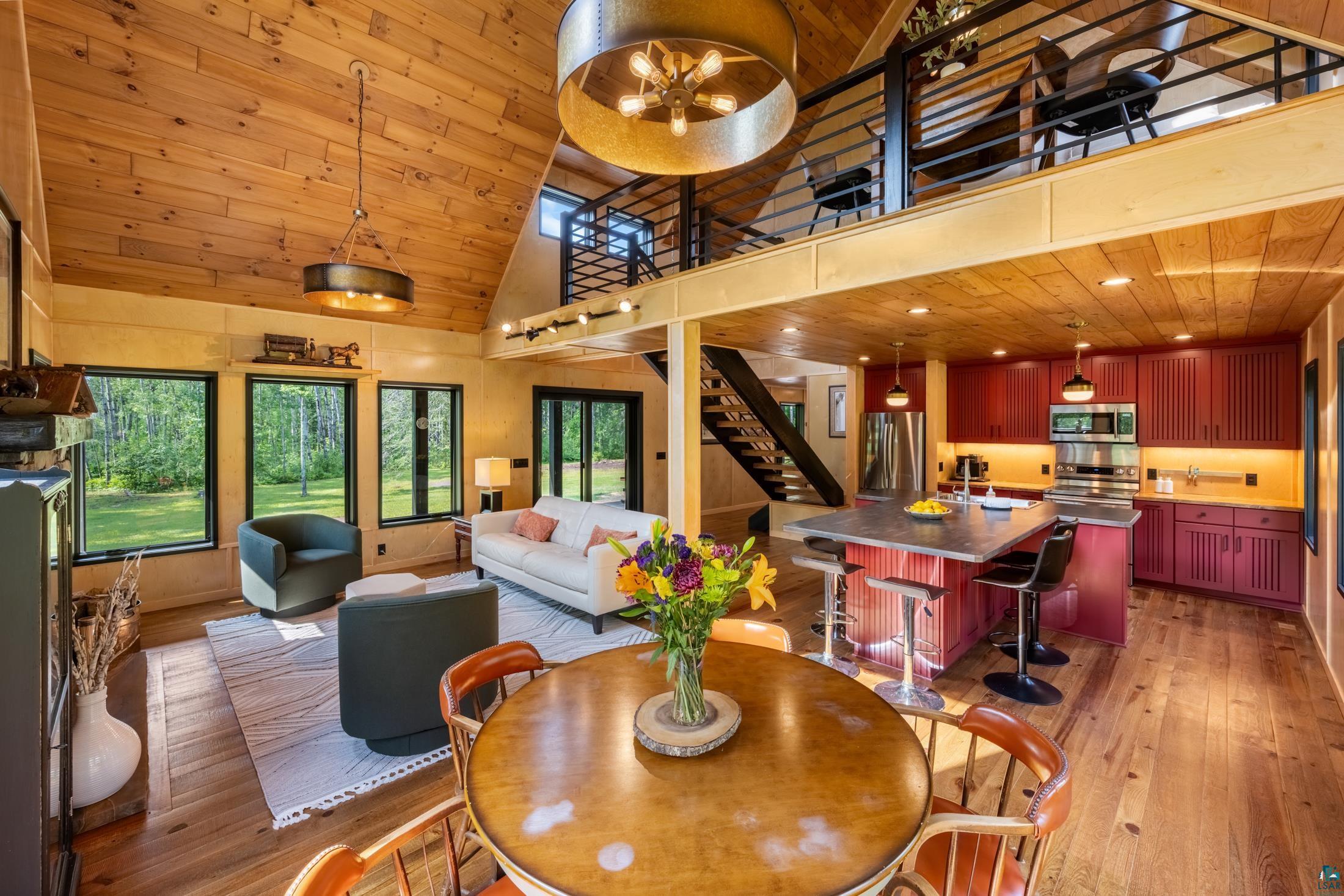 3778 East County Road Barnum, MN 55707 - Photo 30 of 52 Vaulted wood-finish ceiling, open-concept living area, red cabinetry kitchen with island, stainless steel appliances, and a mezzanine with metal railing