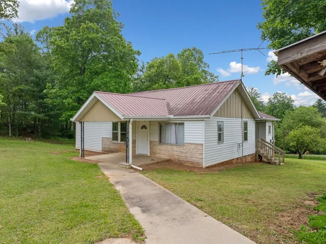 a view of a house with a yard and chairs
